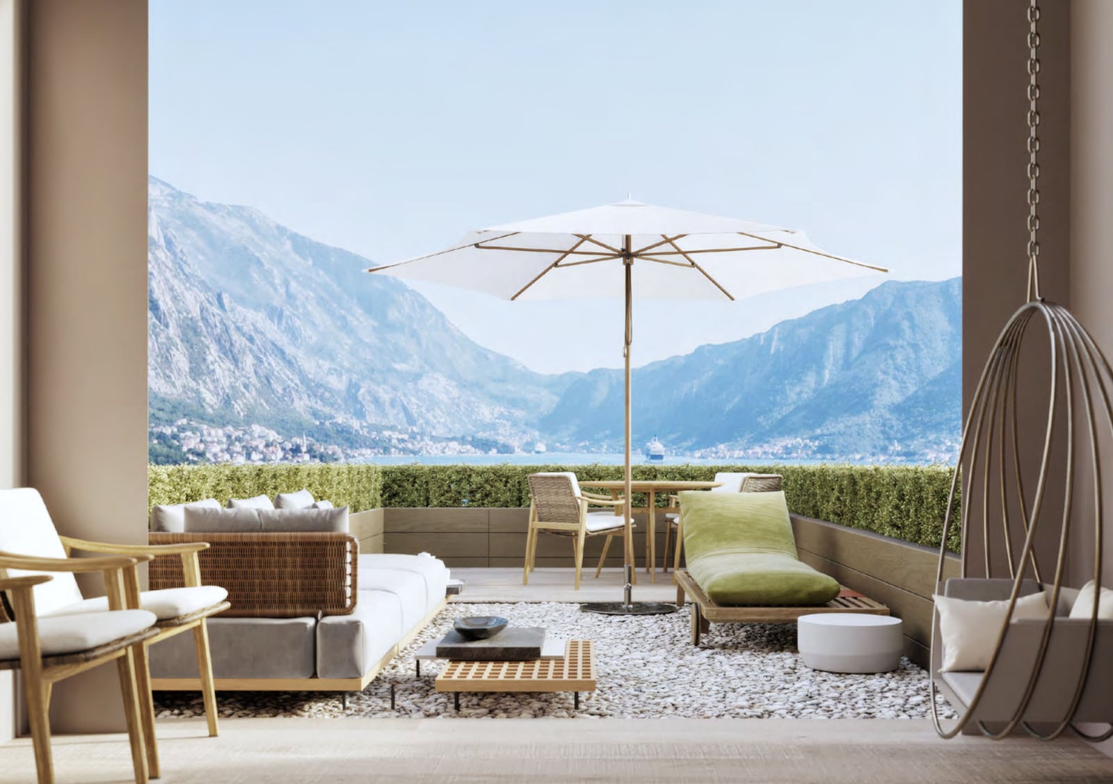 Spacious balcony of a luxury apartment in Orahovac, Montenegro, with wicker furniture, an umbrella, and panoramic views of the sea and mountains.
