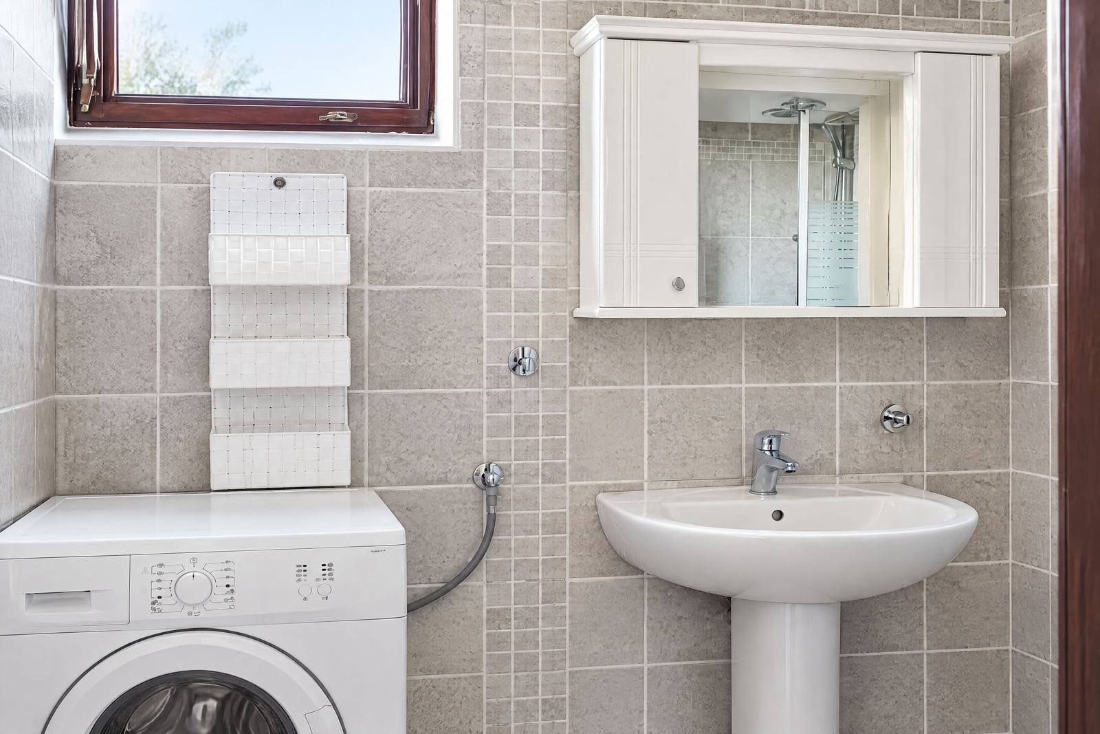 Bright bathroom with a sink, washing machine, and mirror in an apartment in Becici, Montenegro