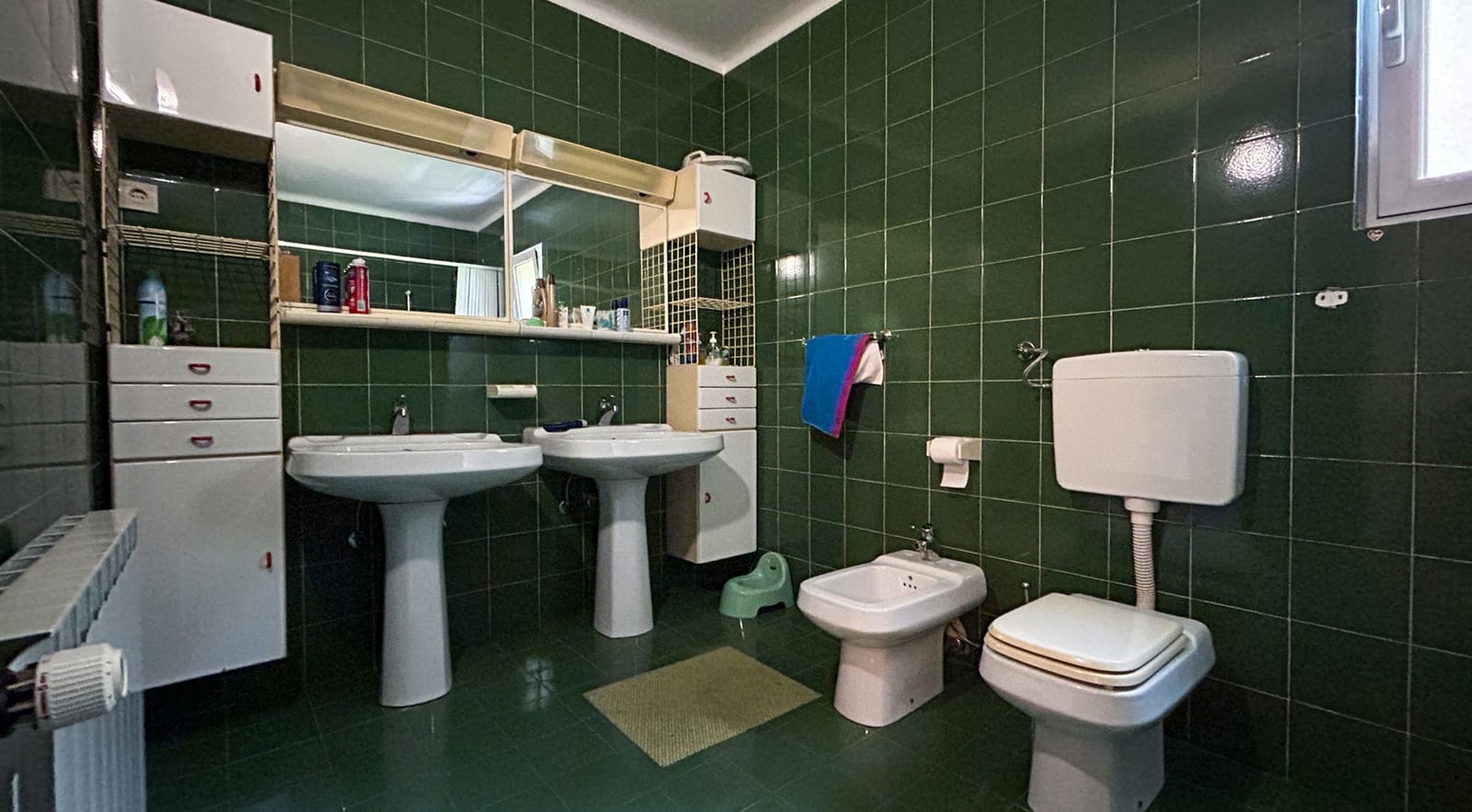 Badezimmer mit grünen Fliesen, zwei Waschbecken und Bidet in einer Villa in Dobrota, Montenegro.