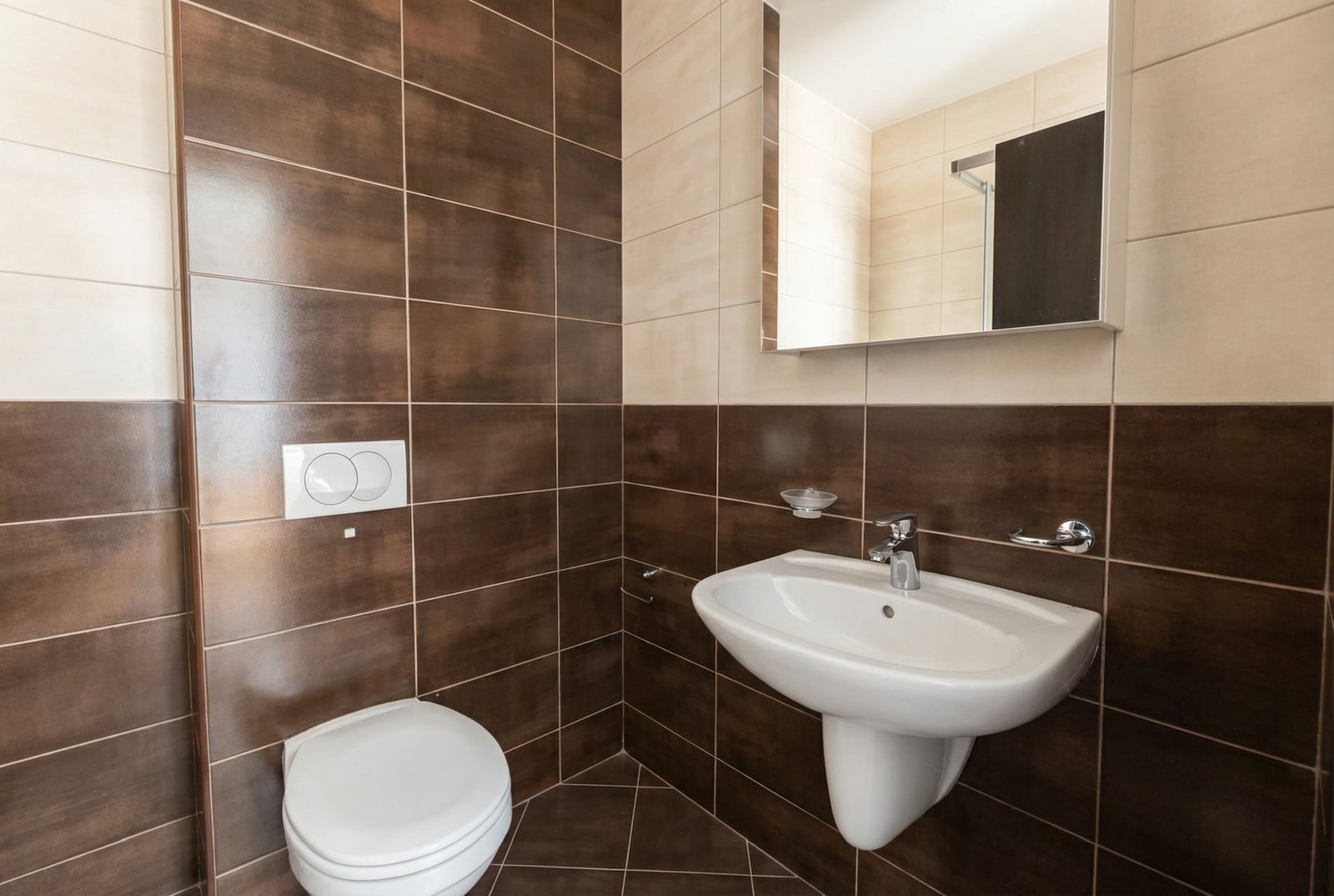 Savremeno kupatilo sa braon pločicama, umivaonikom i visećom WC šoljom u stanu, Budva, Crna Gora.