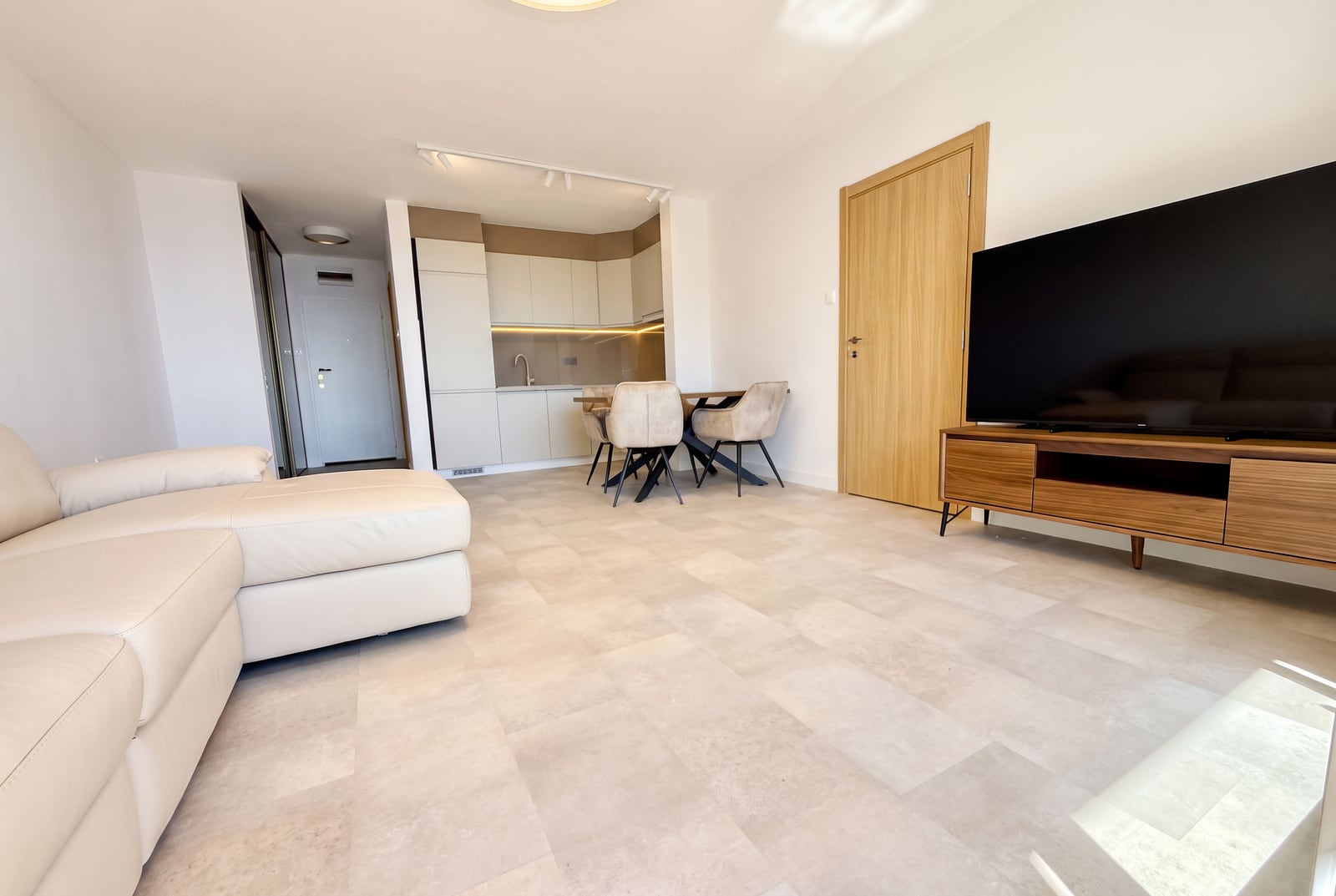 Modern living room with kitchen in an apartment in Sveti Stefan, Montenegro: light sofa, dining area, and TV console.