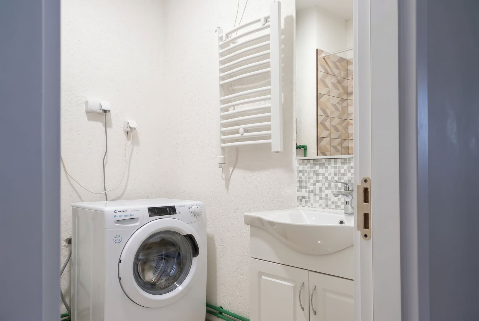 Bright bathroom in a Budva apartment, Montenegro: washing machine, vanity sink, and heated towel rail.