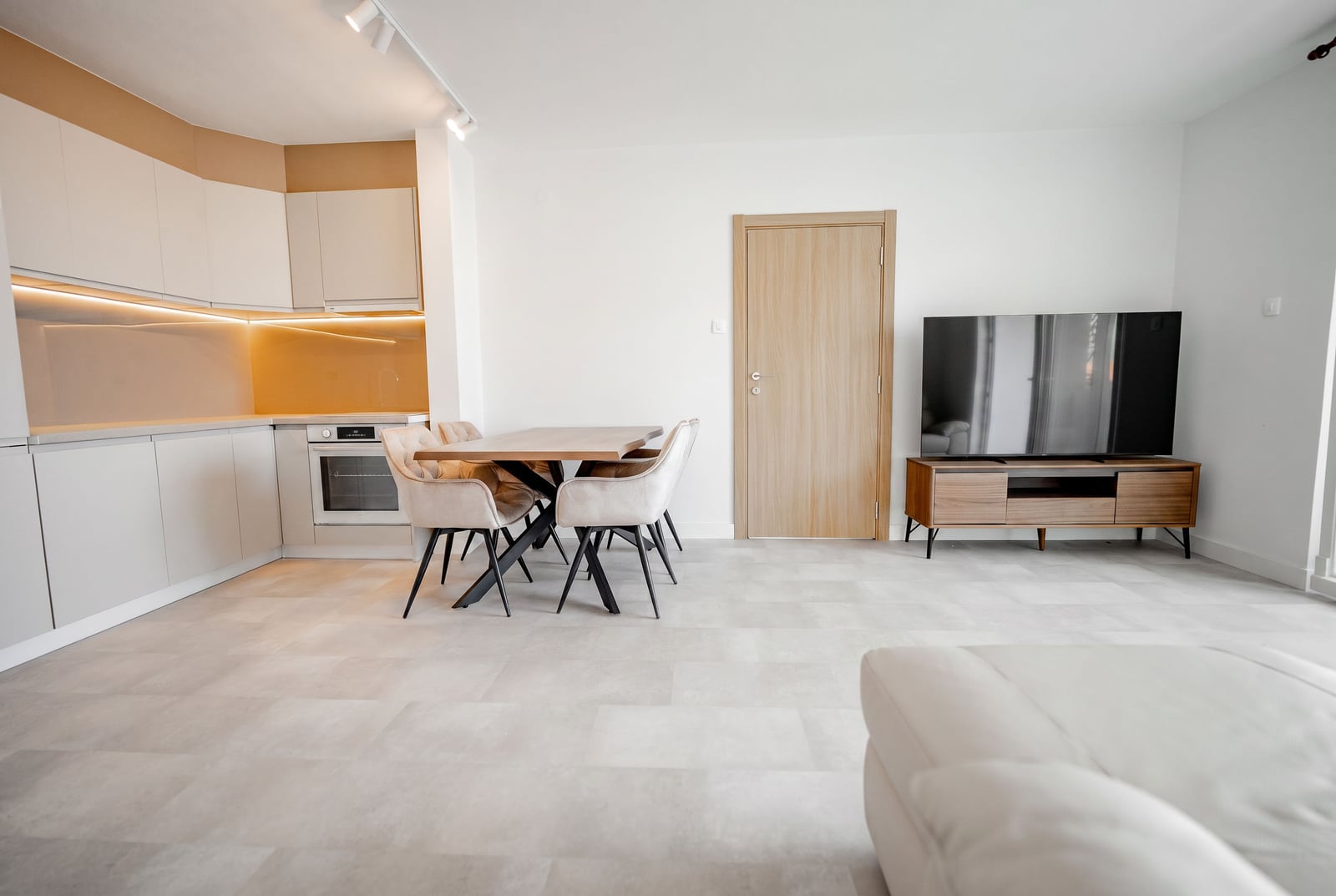 Modern living room with kitchen in an apartment in Sveti Stefan, Montenegro: dining area, light furniture, and TV stand.