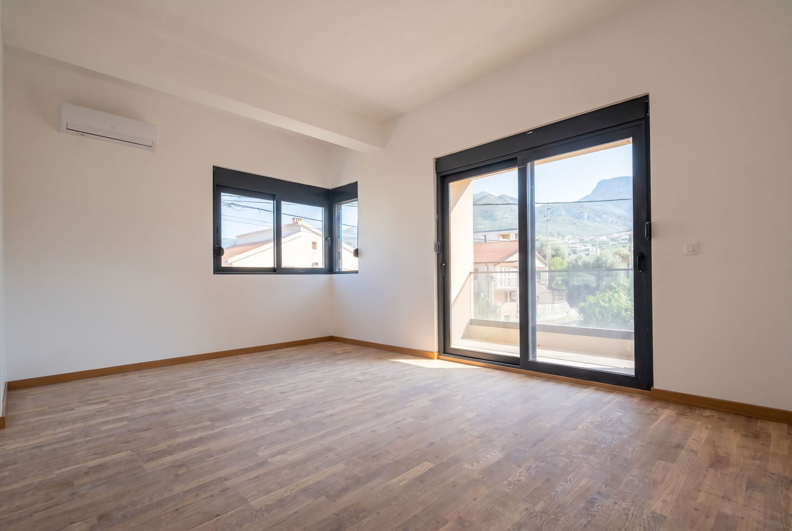 Bright living room with panoramic windows, parquet flooring, and mountain views in an apartment, Bar, Montenegro.