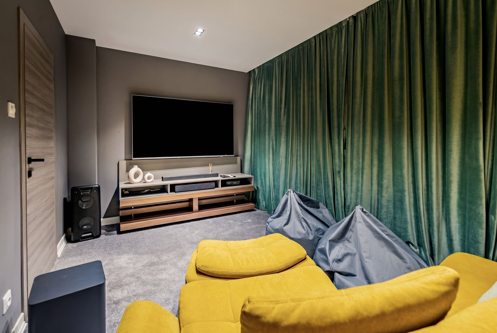 Modern living room with a TV area in a villa, Kumbor, Montenegro: yellow sofa, bean bag chairs, and green curtains.