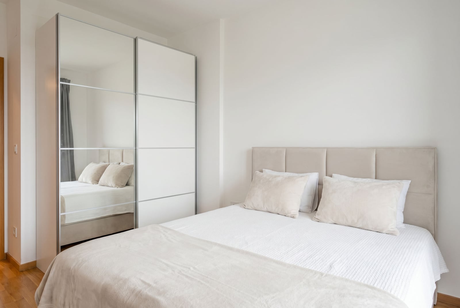 Bright bedroom with a double bed and a mirrored sliding-door wardrobe in an apartment, Becici, Montenegro.