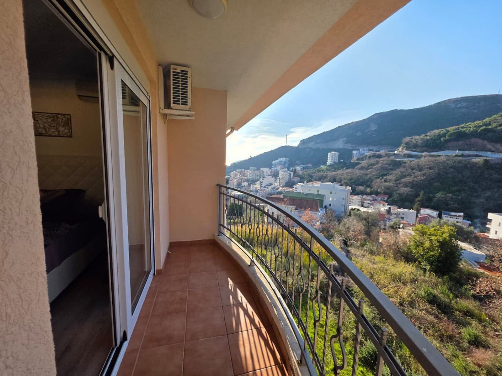 Balkon s panoramskim pogledom na planine i grad Bečići, Crna Gora, izlaz iz spavaće sobe, pločice, kovane ograde.