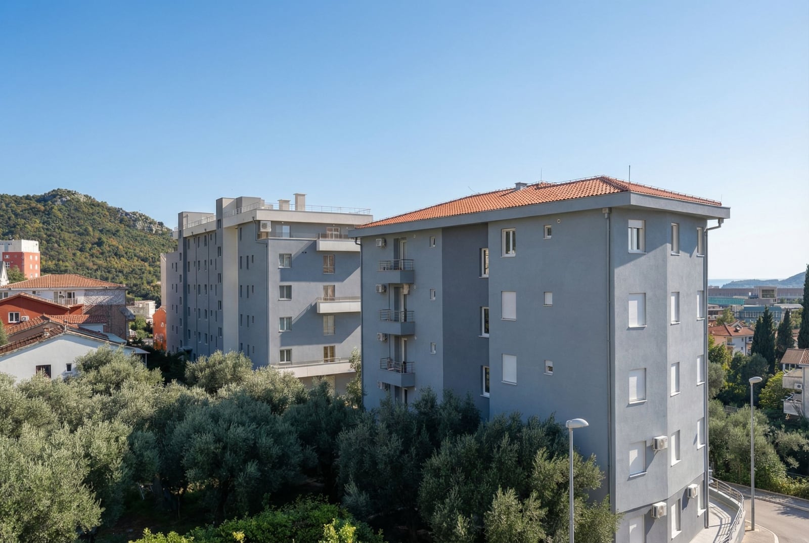 Savremene stambene zgrade sa krovovima od crepa, okružene maslinama, Bečići, Crna Gora.