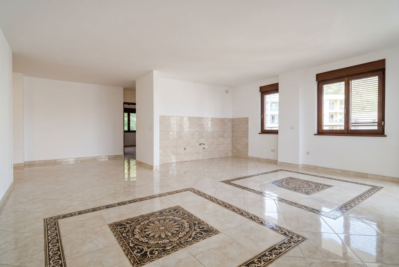 Helles Wohnzimmer mit Fliesenboden und Küchenbereich in einer zum Verkauf stehenden Wohnung in Bečići, Montenegro.