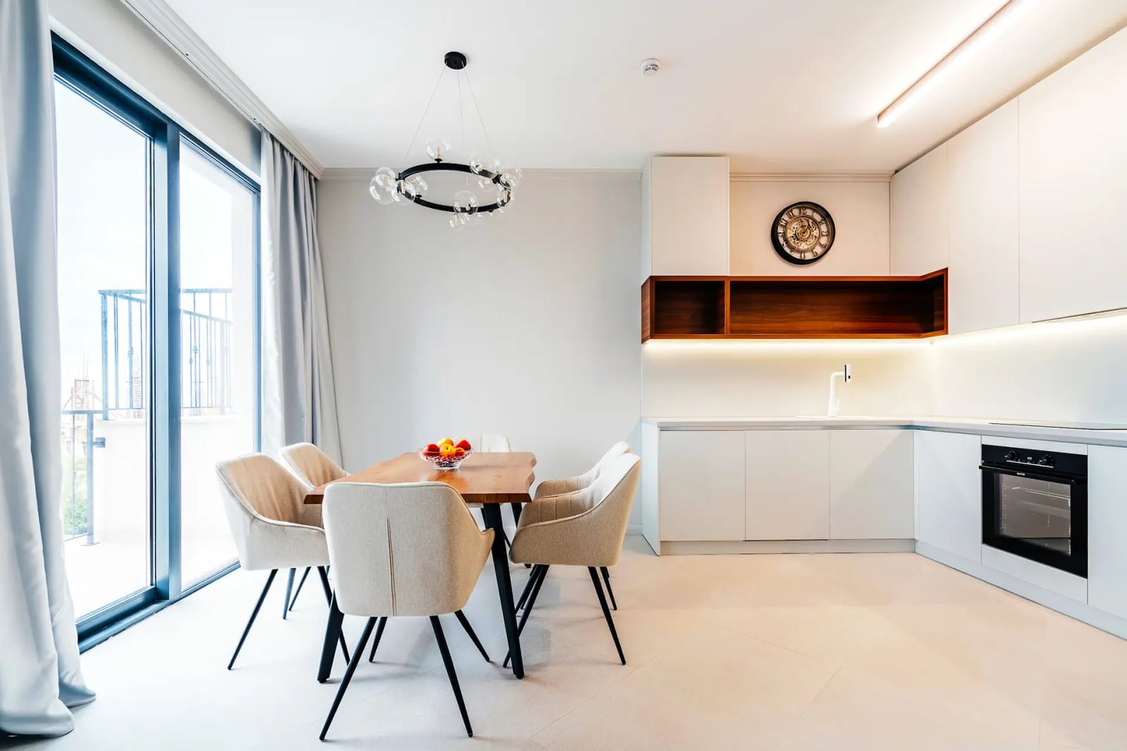 Modern kitchen-dining room in a villa in Reževići, Montenegro: white cabinetry, wooden table, and panoramic windows.