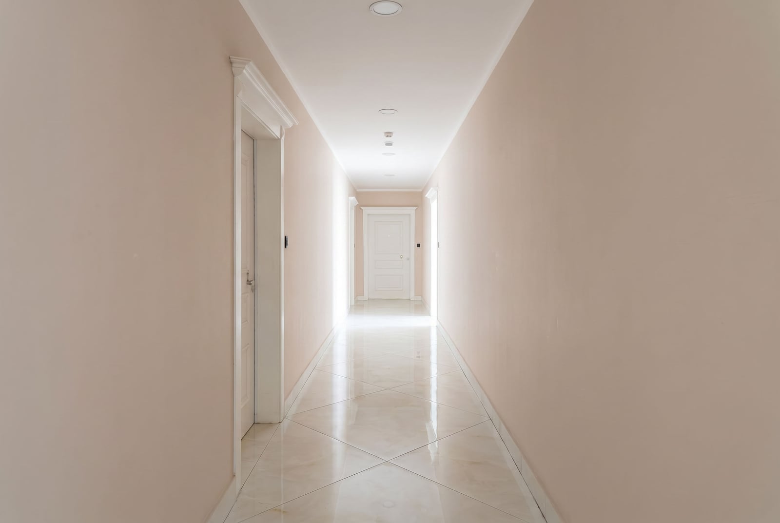 Bright hallway with white doors and glossy tiled floors in an apartment, Budva, Montenegro.