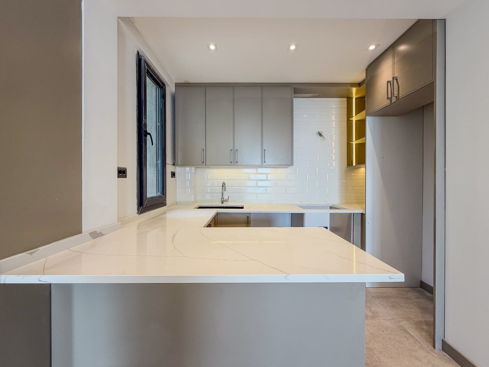 Modern kitchen with a white countertop and gray cabinetry in an apartment in Budva, Montenegro