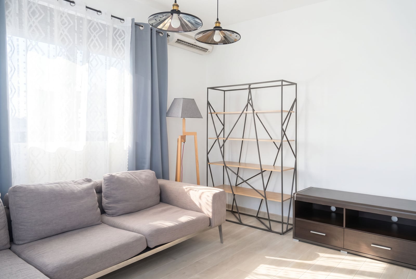 Helle Wohnzimmer mit grauem Sofa, Regal und Kommode in einer Wohnung in Budva, Montenegro