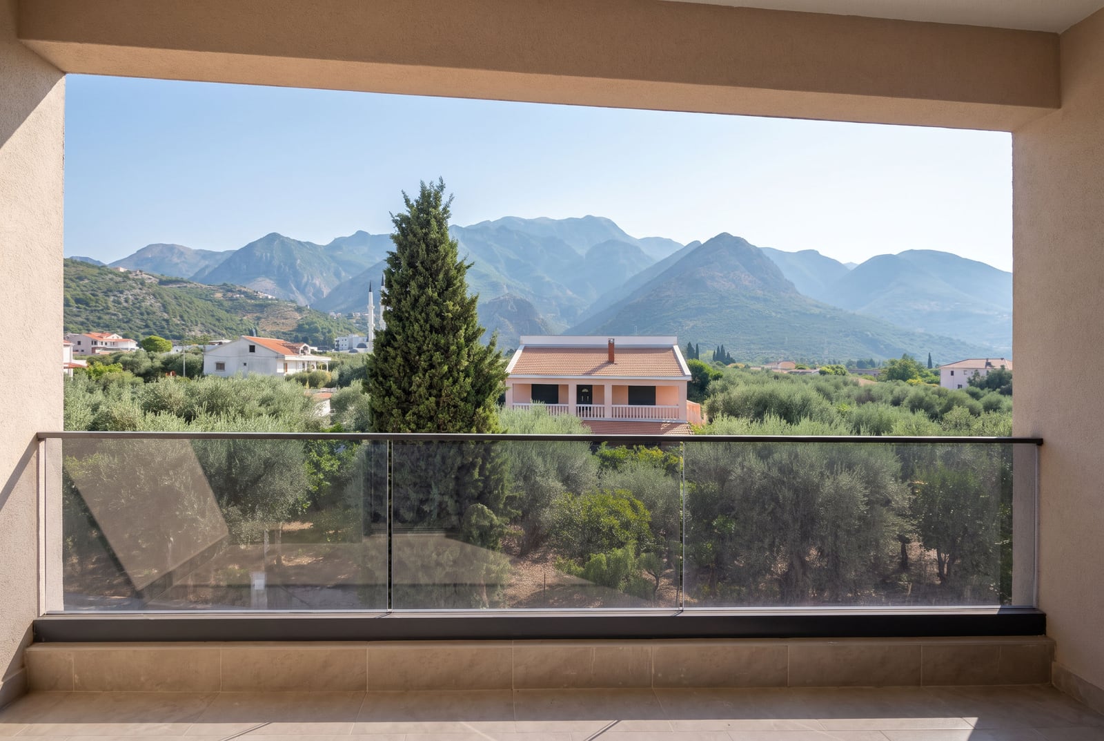 View from the apartment balcony in Bar, Montenegro: glass railing, olive trees, and panoramic mountains in the background.