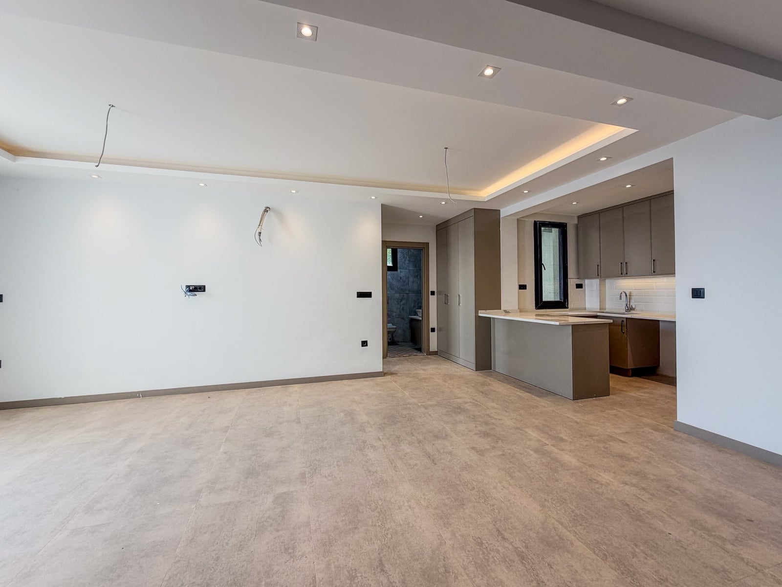 Modern living room with kitchen and white finish in a new apartment in Budva, Montenegro