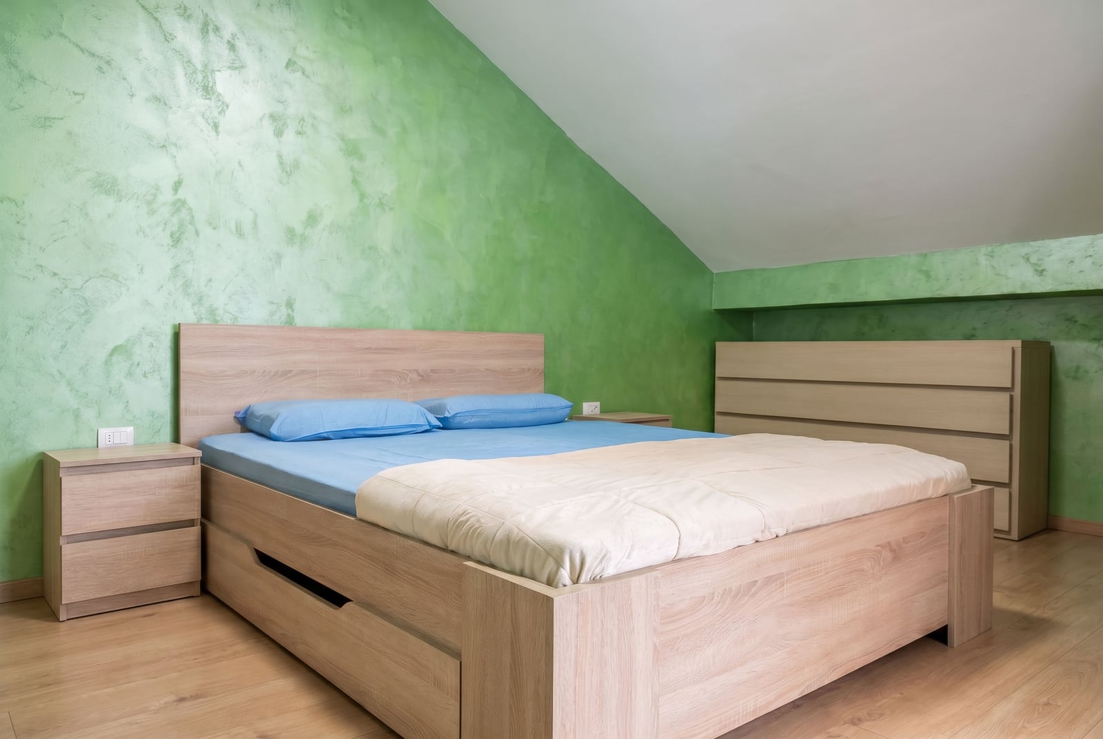 Bedroom in a Budva apartment, Montenegro: double bed, light wood furniture, and green painted walls.