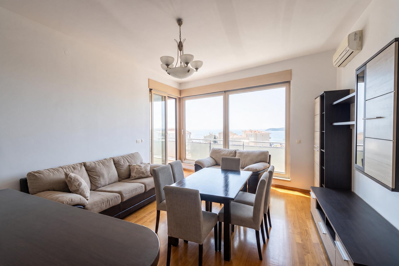 Living room with panoramic windows, furniture, and a dining area in an apartment in Bečići, Montenegro.