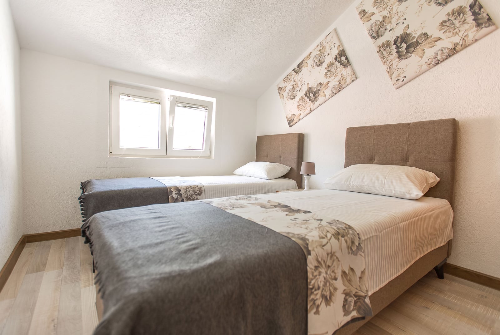 Bright bedroom with two single beds and a window in an apartment in Budva, Montenegro