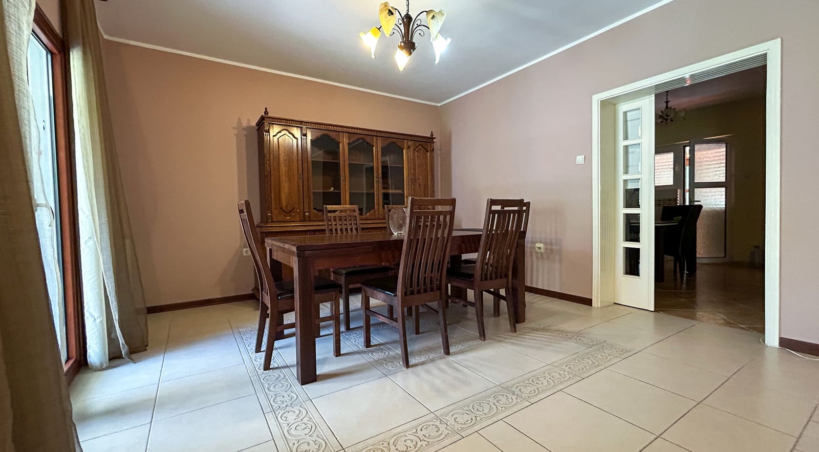 Geräumiges Wohnzimmer mit hölzerner Essgruppe in einer Villa in Dobrota, Montenegro: Fliesenboden und klassischer Stil.