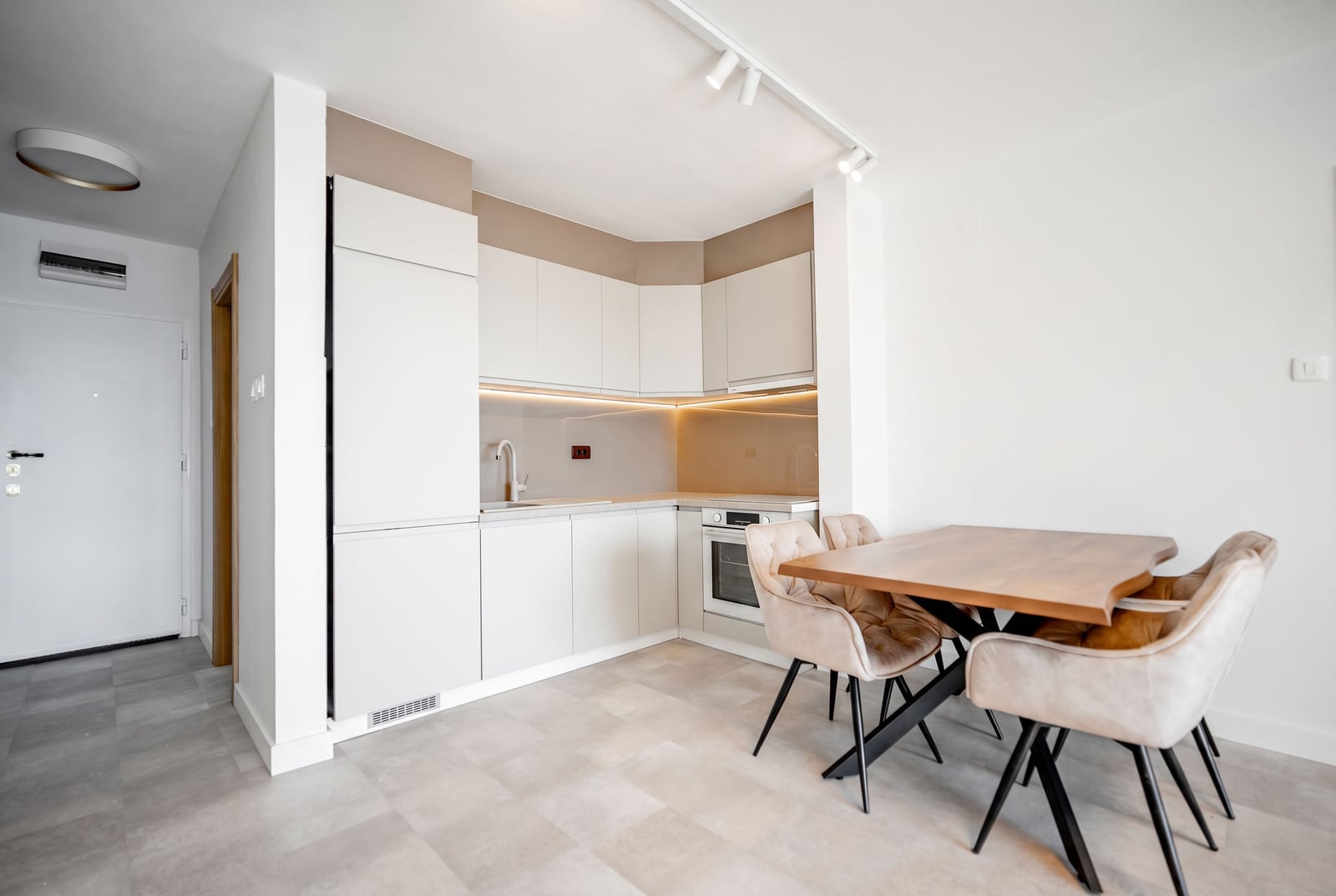 Modern kitchen-dining area in an apartment, Sveti Stefan, Montenegro: light-colored kitchen unit, dining table, and upholstered chairs.