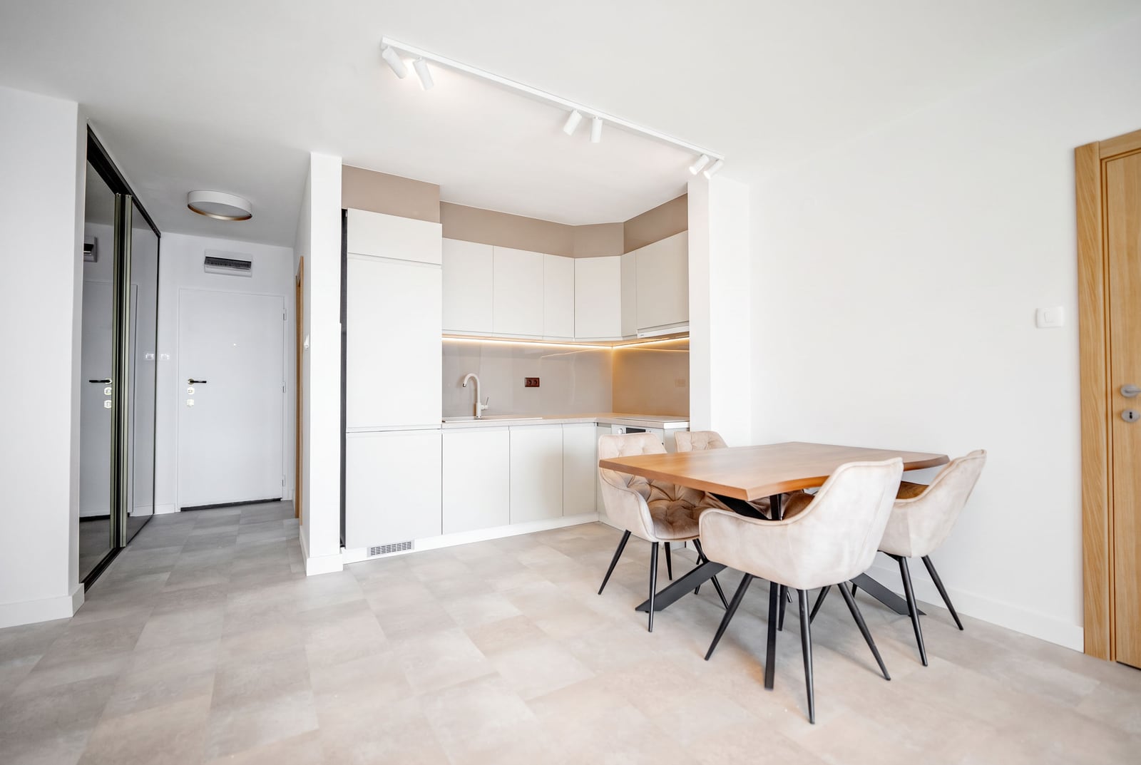 Modern kitchen-dining area in an apartment, Sveti Stefan, Montenegro: light-colored kitchen unit, dining table, and upholstered chairs.