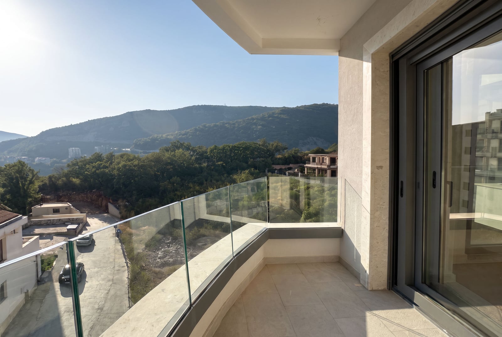 Balcon avec vue panoramique sur les montagnes et garde-corps en verre dans un appartement à Bečići, Monténégro