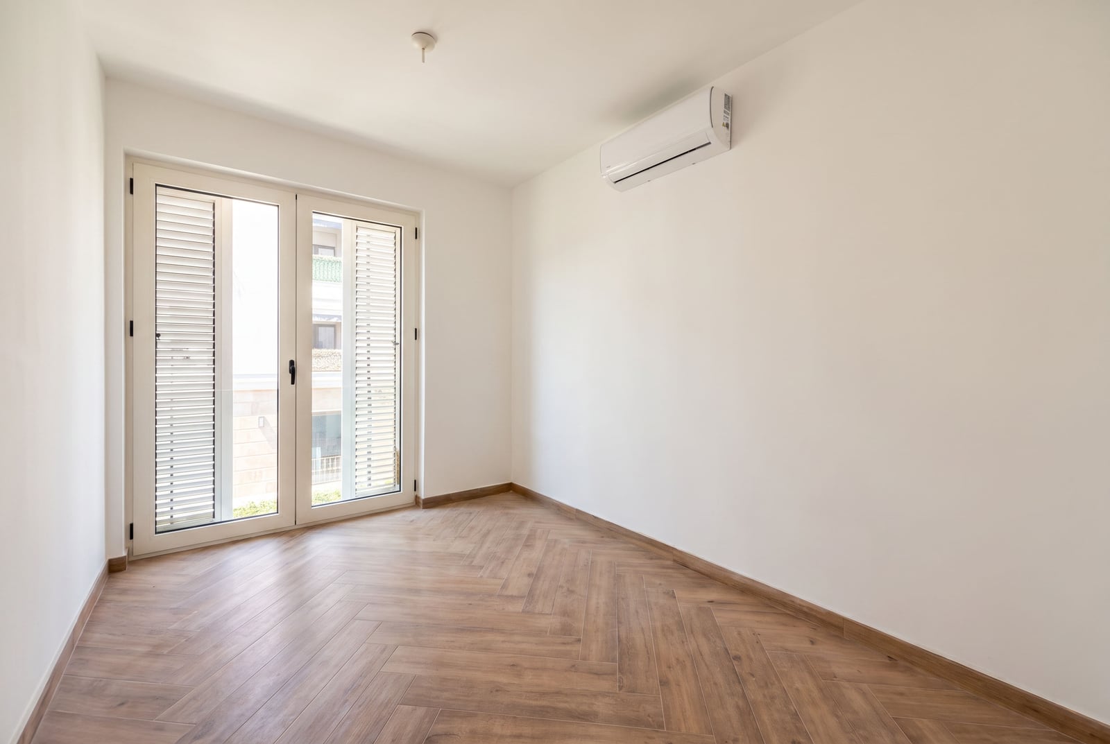 Bright empty living room with herringbone parquet flooring and air conditioning in an apartment in Tivat, Montenegro.