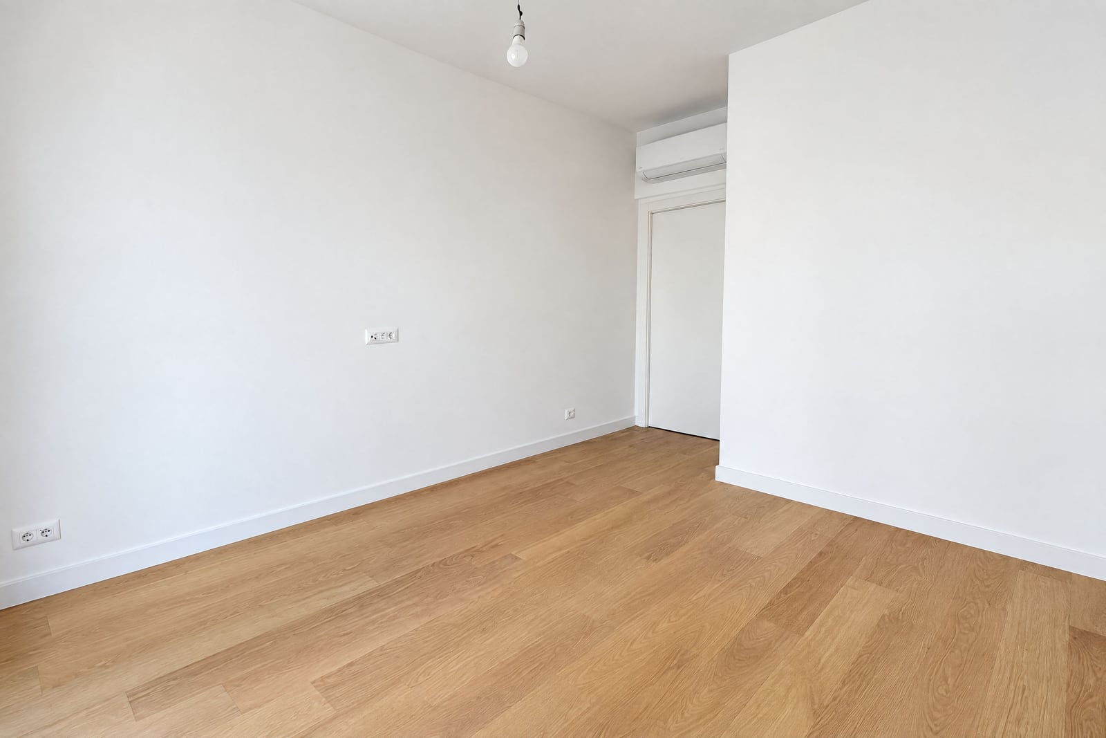 Chambre lumineuse et vide avec murs blancs, sol stratifié et climatisation dans un appartement à Bečići, Monténégro