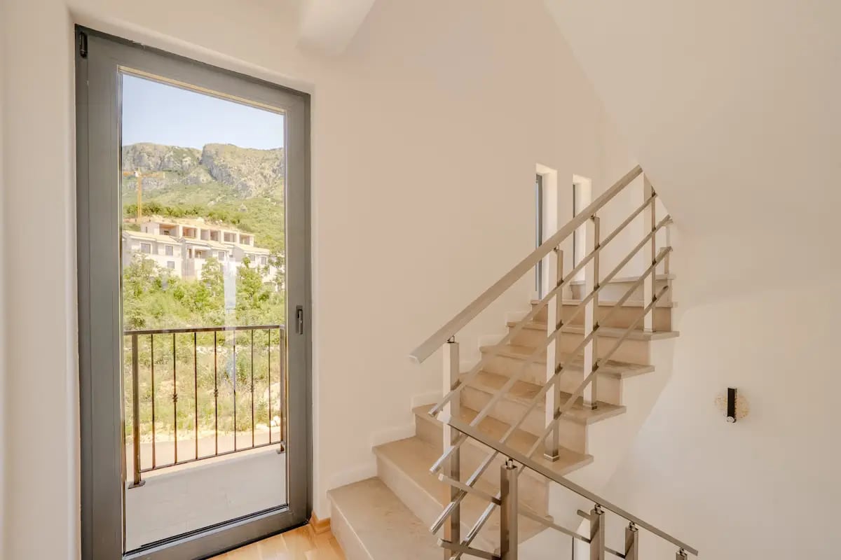 Staircase with metal railings and panoramic door with a mountain view in a villa, Reževići, Montenegro.