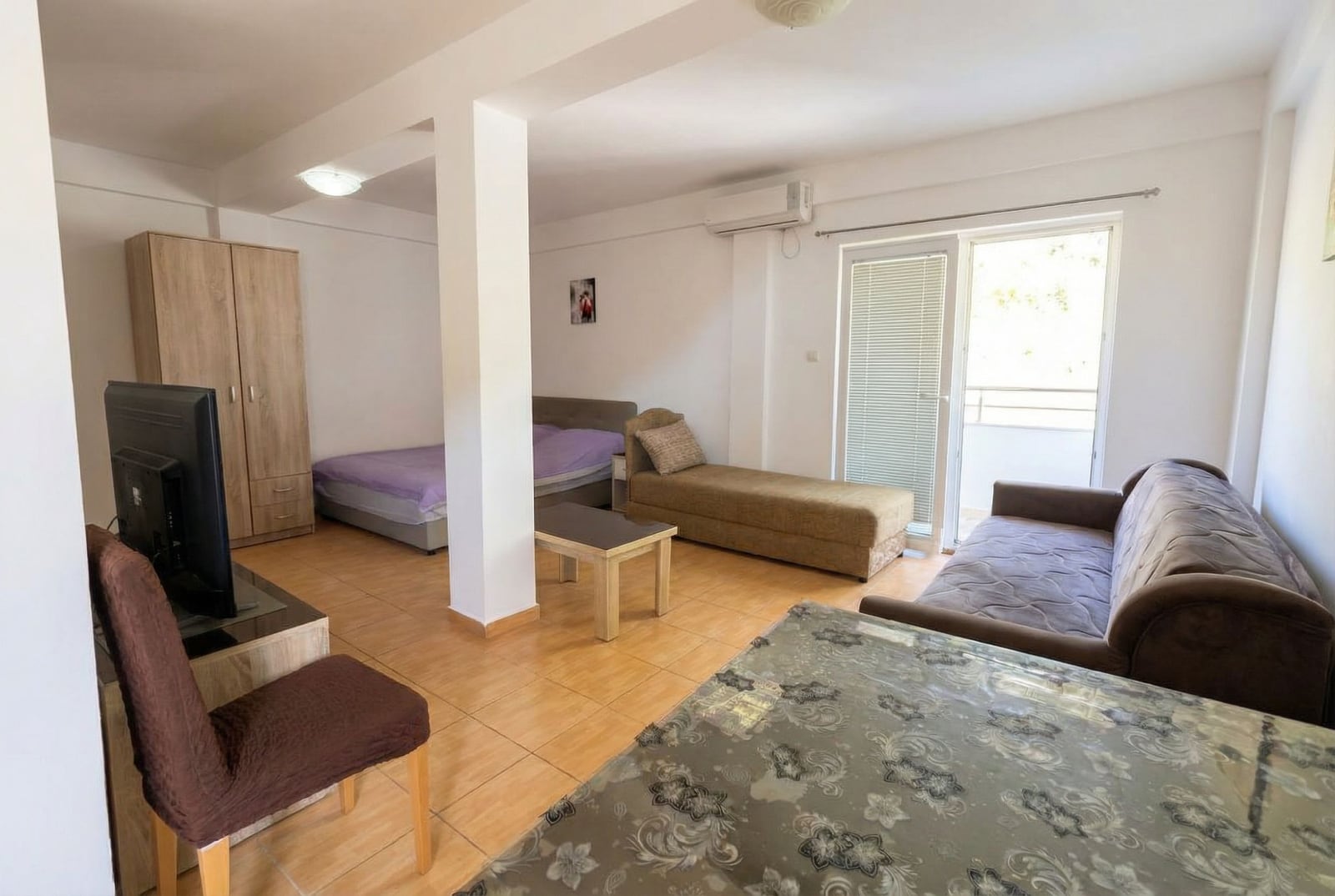 Svetao studio u Budvi, Crna Gora: dnevna soba sa bračnim krevetom, sofom, TV-om i izlazom na balkon.