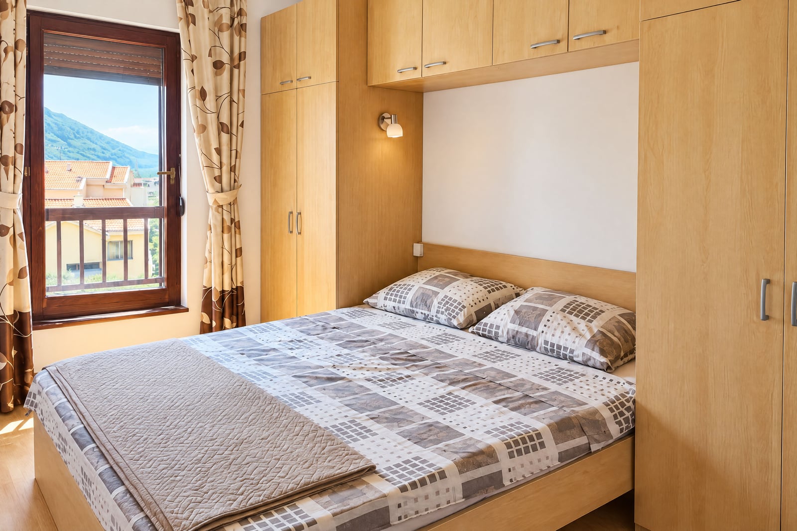 Bedroom with a double bed, built-in wardrobes, and mountain views in an apartment in Becici, Montenegro
