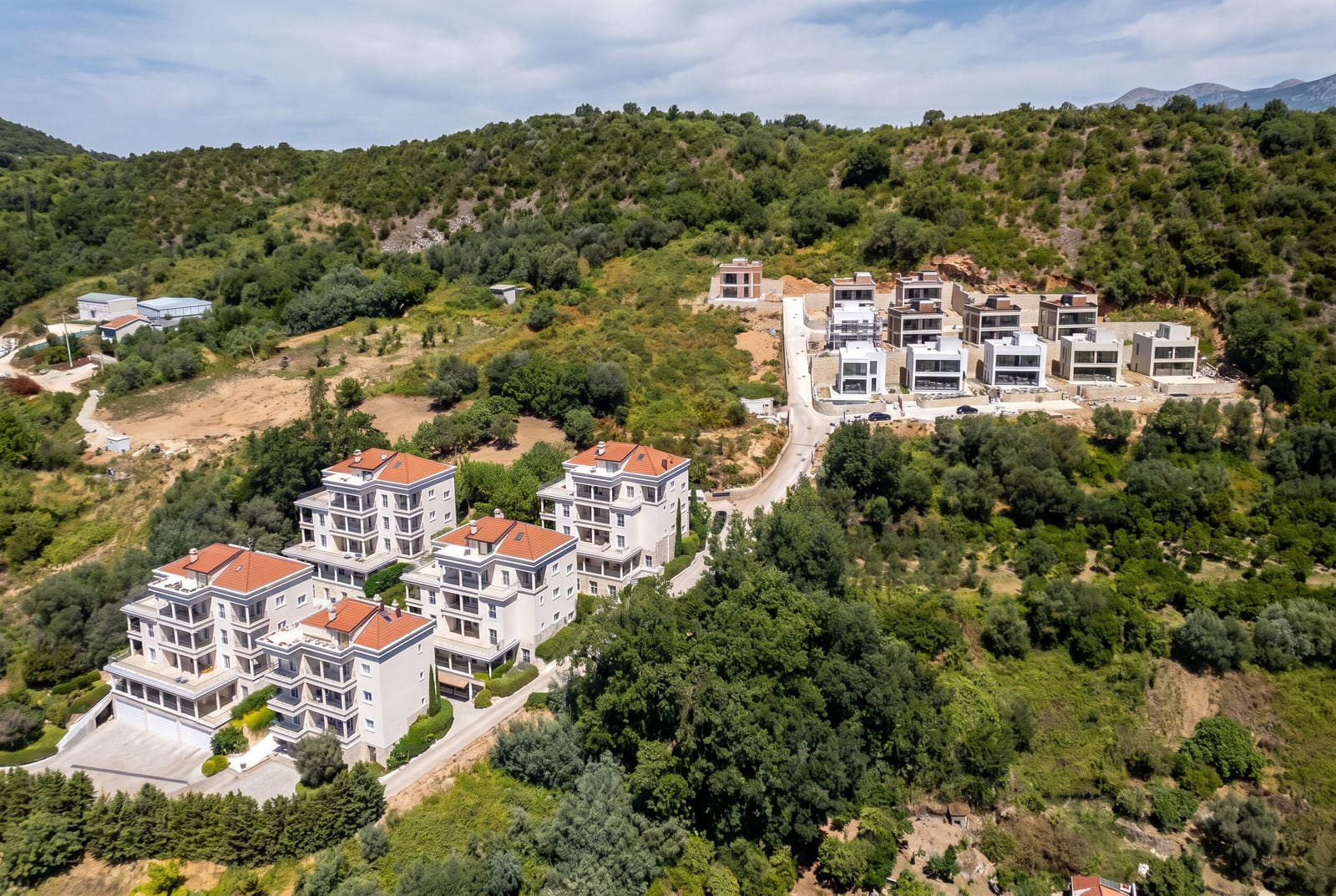 Residential complex of modern villas in Kumbor, Montenegro: aerial view of houses with terraces amidst a green landscape.