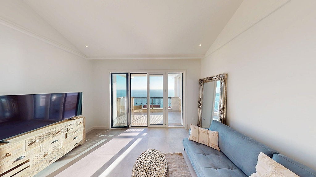 Helles Wohnzimmer in der Apartmentanlage Luštica Bay, Montenegro: blaues Sofa, geschnitzter Schrank und Panoramablick auf das Meer von der Terrasse.