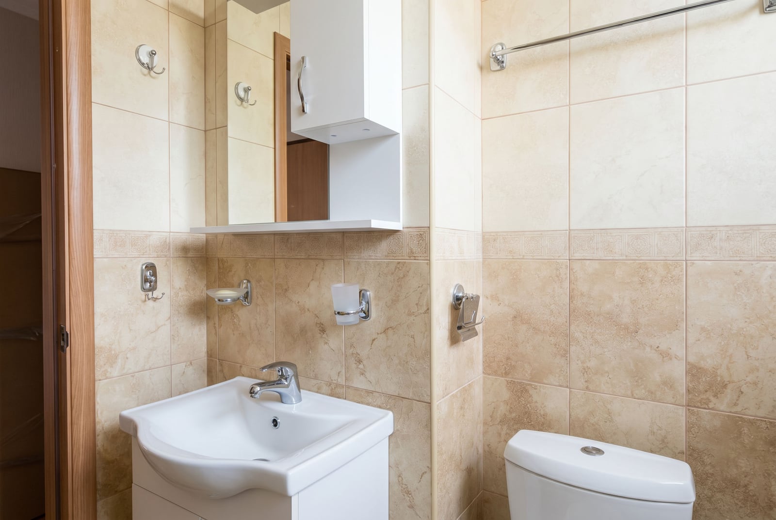 Budva, Karadağ'daki bir dairede beyaz vitrifiye ve bej fayanslara sahip aydınlık banyo.