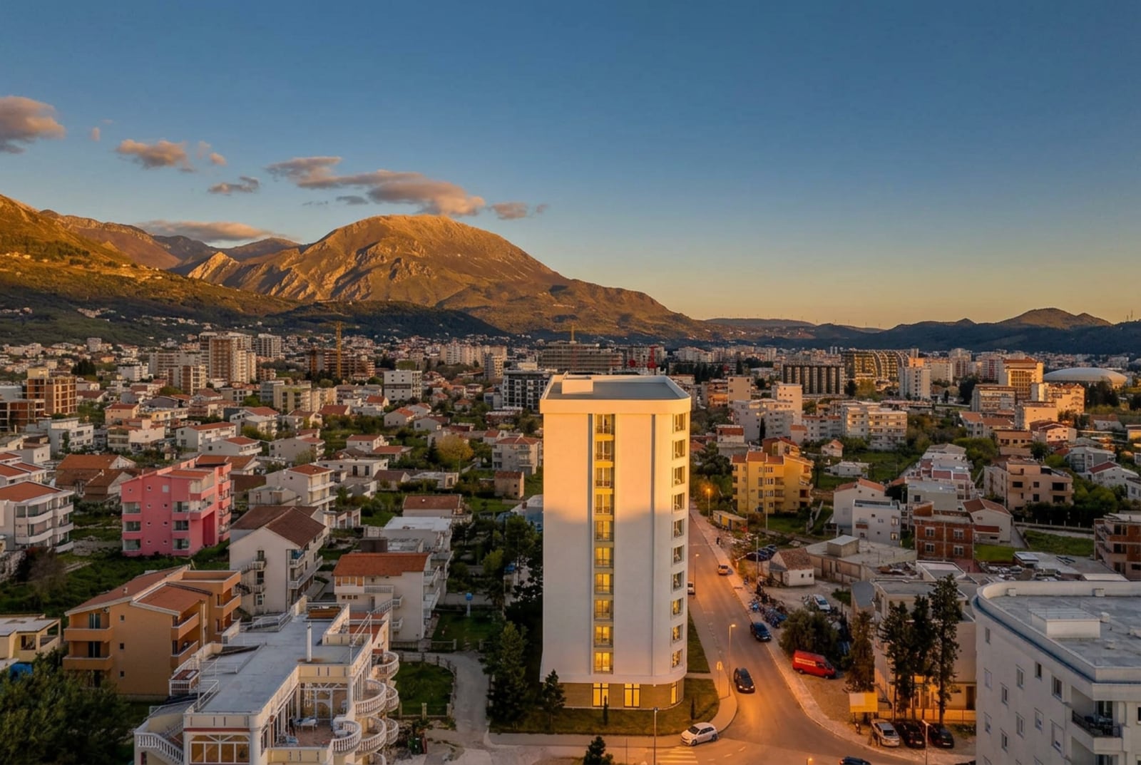 Moderner Wohnkomplex in der Stadt Bar, Montenegro, mit Panoramablick auf die Berge und die Stadtbebauung bei Sonnenuntergang.