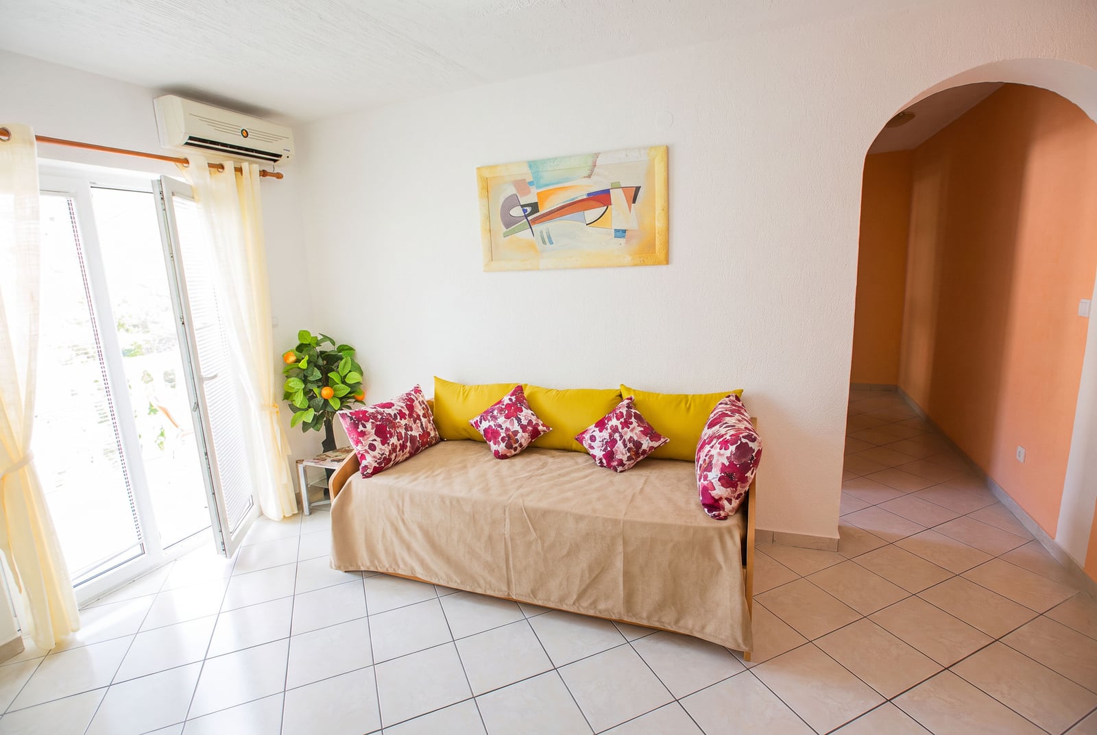 Bright living room with a sofa, painting, and balcony access in an apartment in Budva, Montenegro