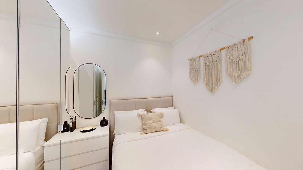 Helles Schlafzimmer in einer Wohnung in Luštica, Montenegro: Doppelbett, Spiegelkleiderschrank und Boho-Dekor.