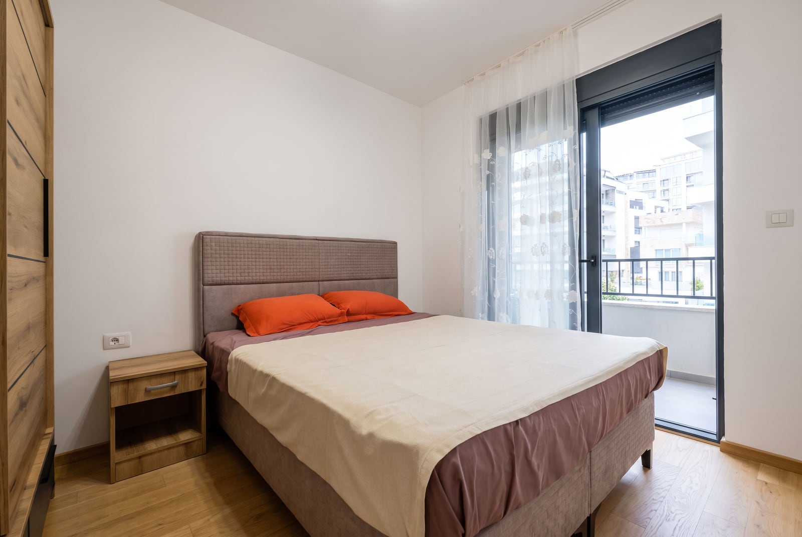 Moderna spavaća soba sa bračnim krevetom, ormanom i izlazom na balkon u stanu u Bečićima, Crna Gora