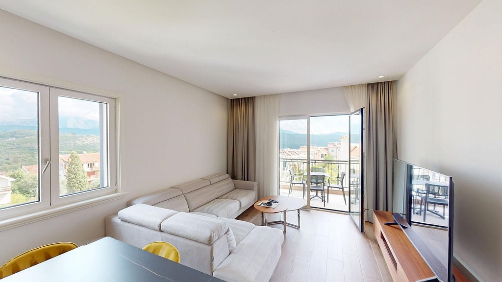 Светлая гостиная с выходом на террасу в квартире Lustica Bay, Черногория: современная мебель и вид на горы.