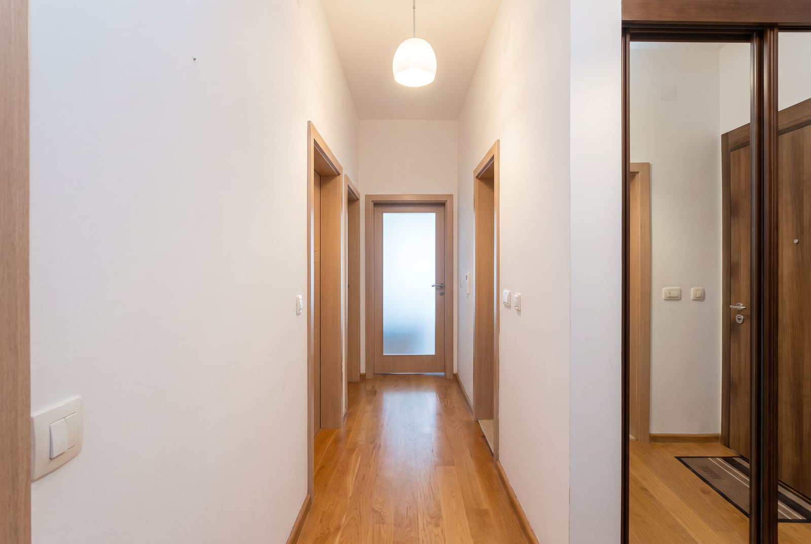 Bright hallway with parquet flooring, interior wooden doors, and a built-in wardrobe in an apartment in Bečići, Montenegro.