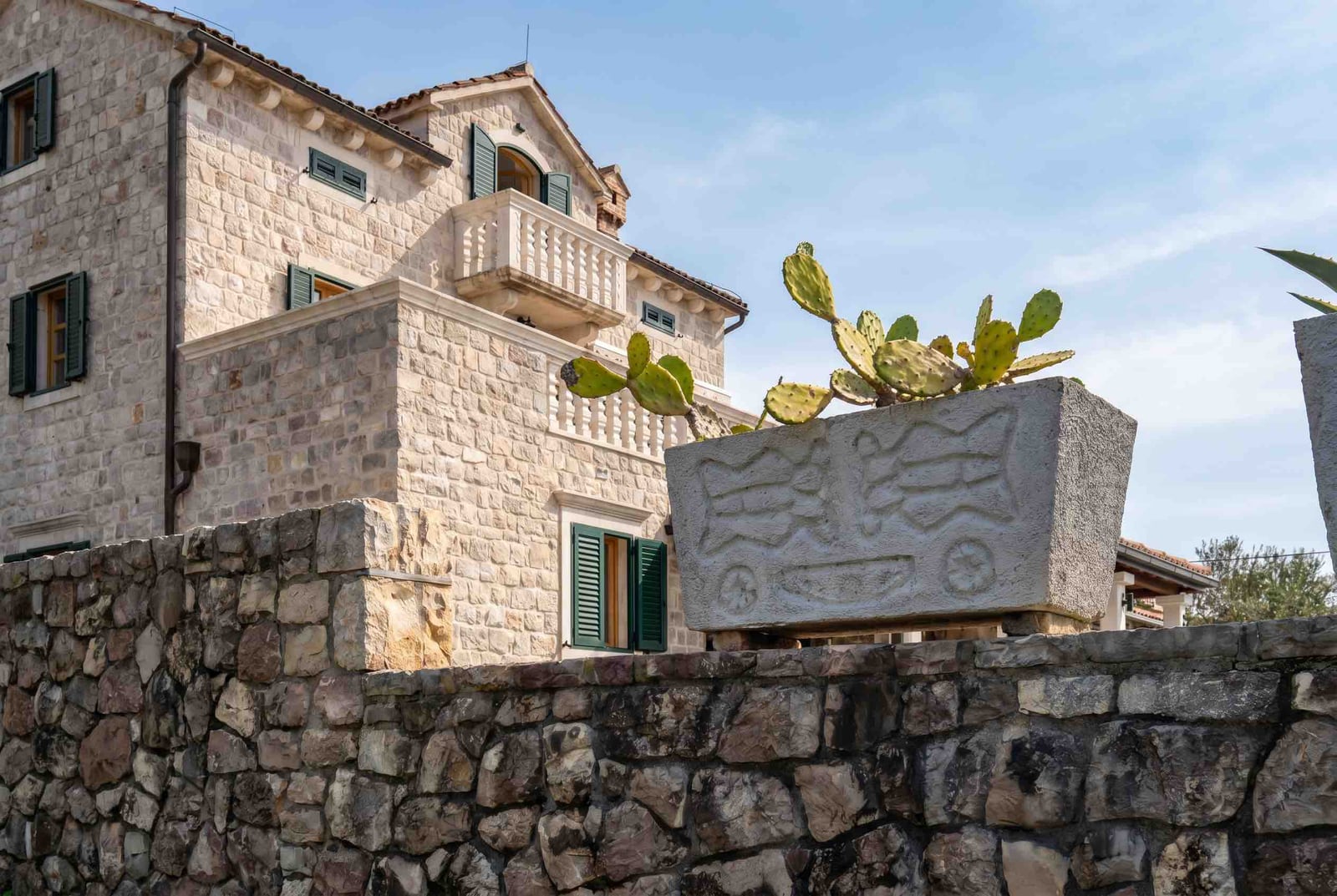 Kamena kuća u mediteranskom stilu sa balkonom i kaktusima u Luštici, Crna Gora. Fasada od prirodnog kamena.