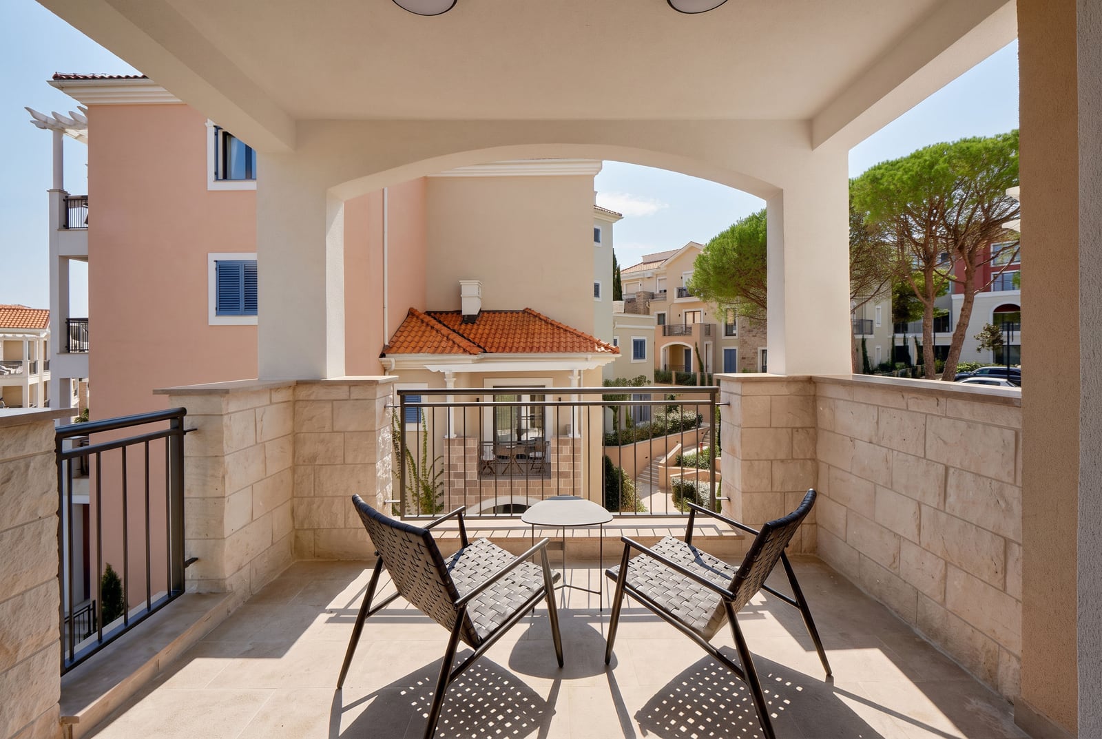 Geräumiger überdachter Balkon mit Rattansesseln und Blick auf die Anlage in Luštica, Montenegro