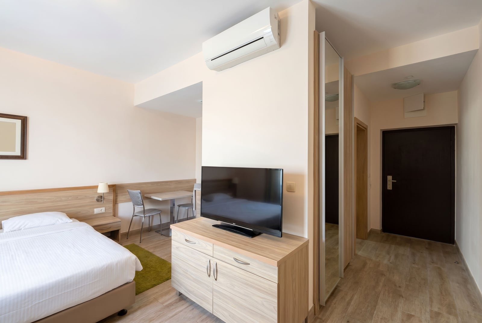 Modern bedroom in an apartment in Bečići, Montenegro: double bed, TV area, air conditioning, and mirrored wardrobe.