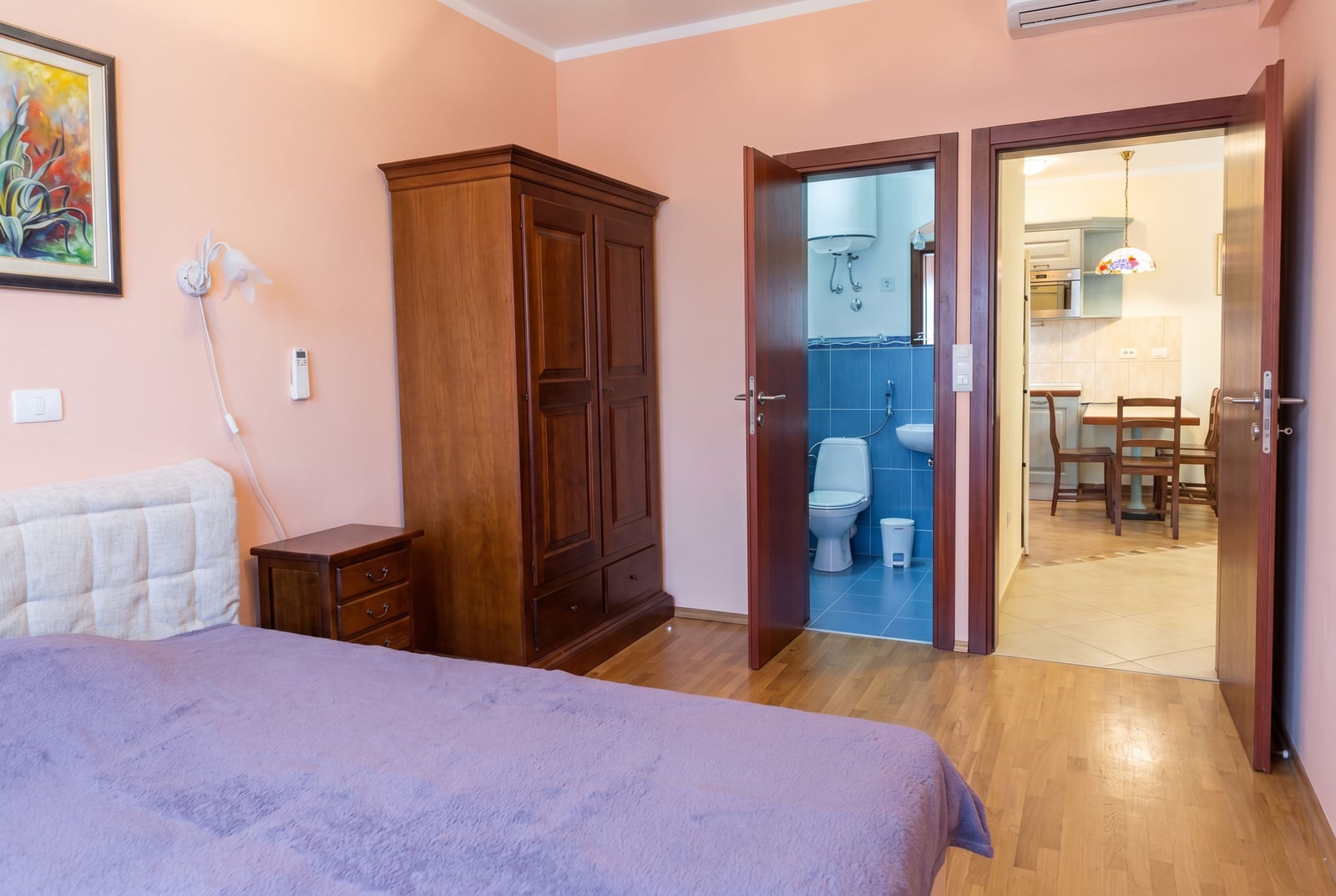 Spavaća soba u stanu u Baru, Crna Gora: drveni ormar, bračni krevet, pogled na kupatilo i kuhinju.