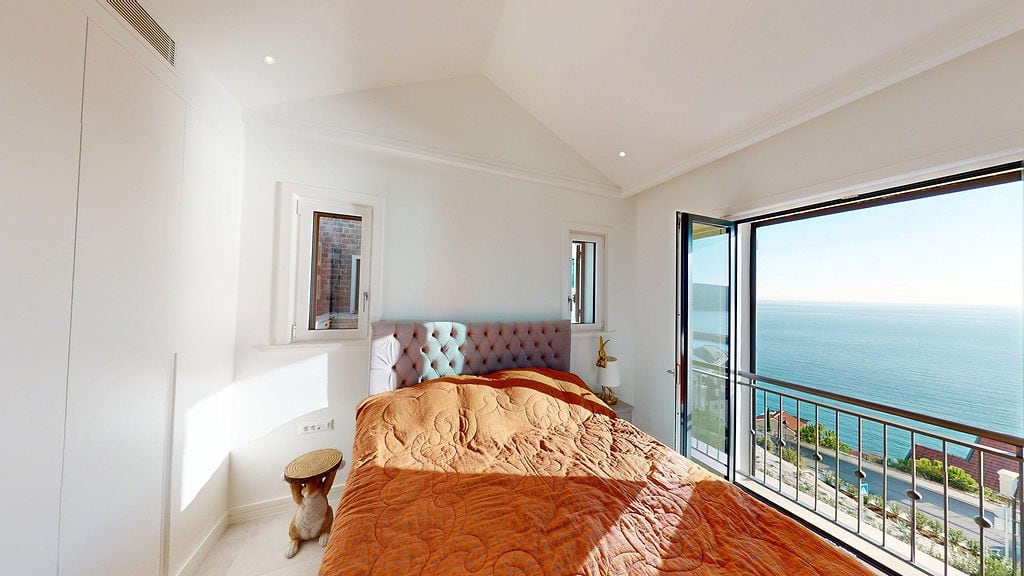 Helles Schlafzimmer mit Bett und Panoramablick auf das Meer in einer Wohnung, Luštica, Montenegro.