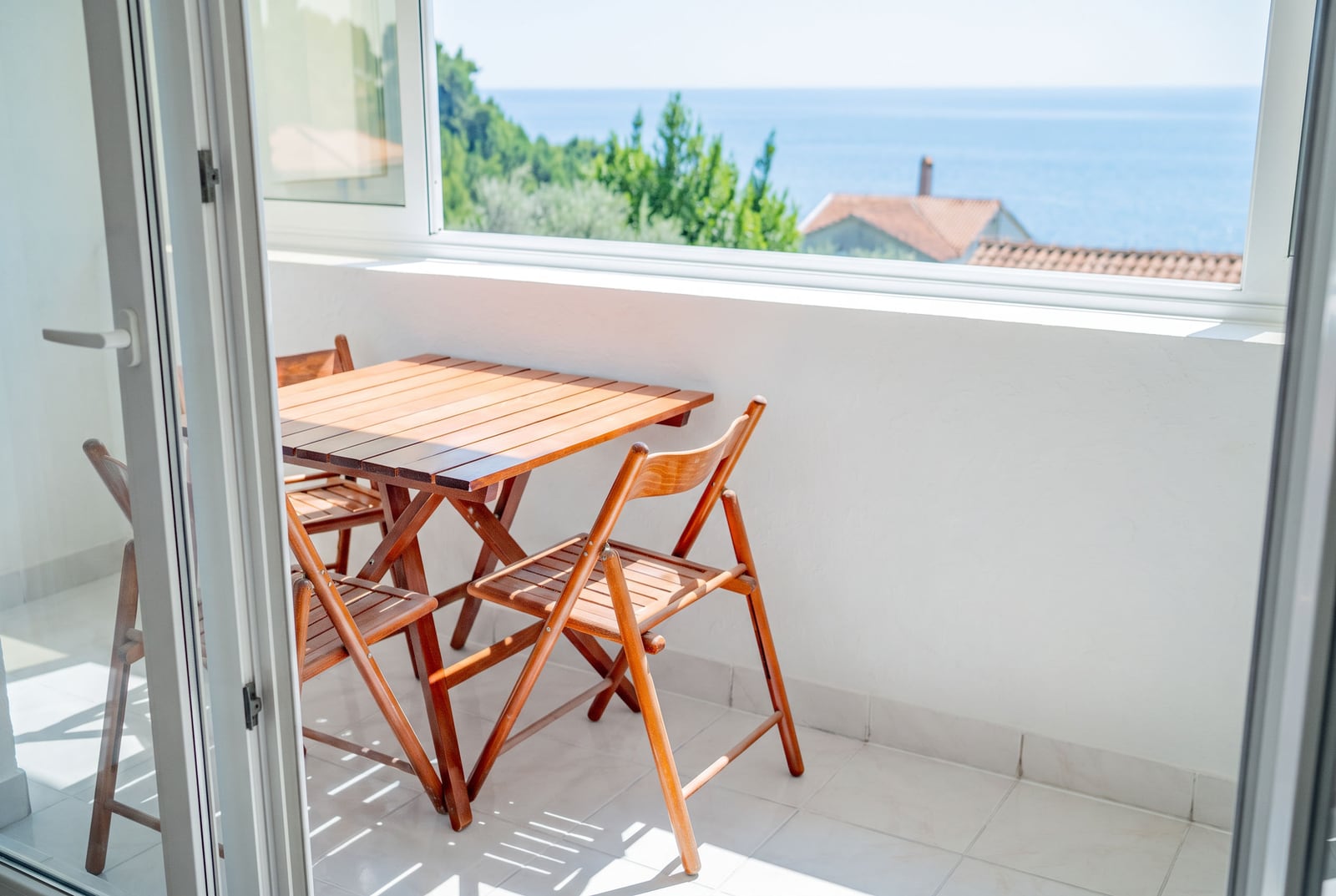 Balcony with wooden furniture and panoramic sea view in an apartment, Sveti Stefan, Montenegro.