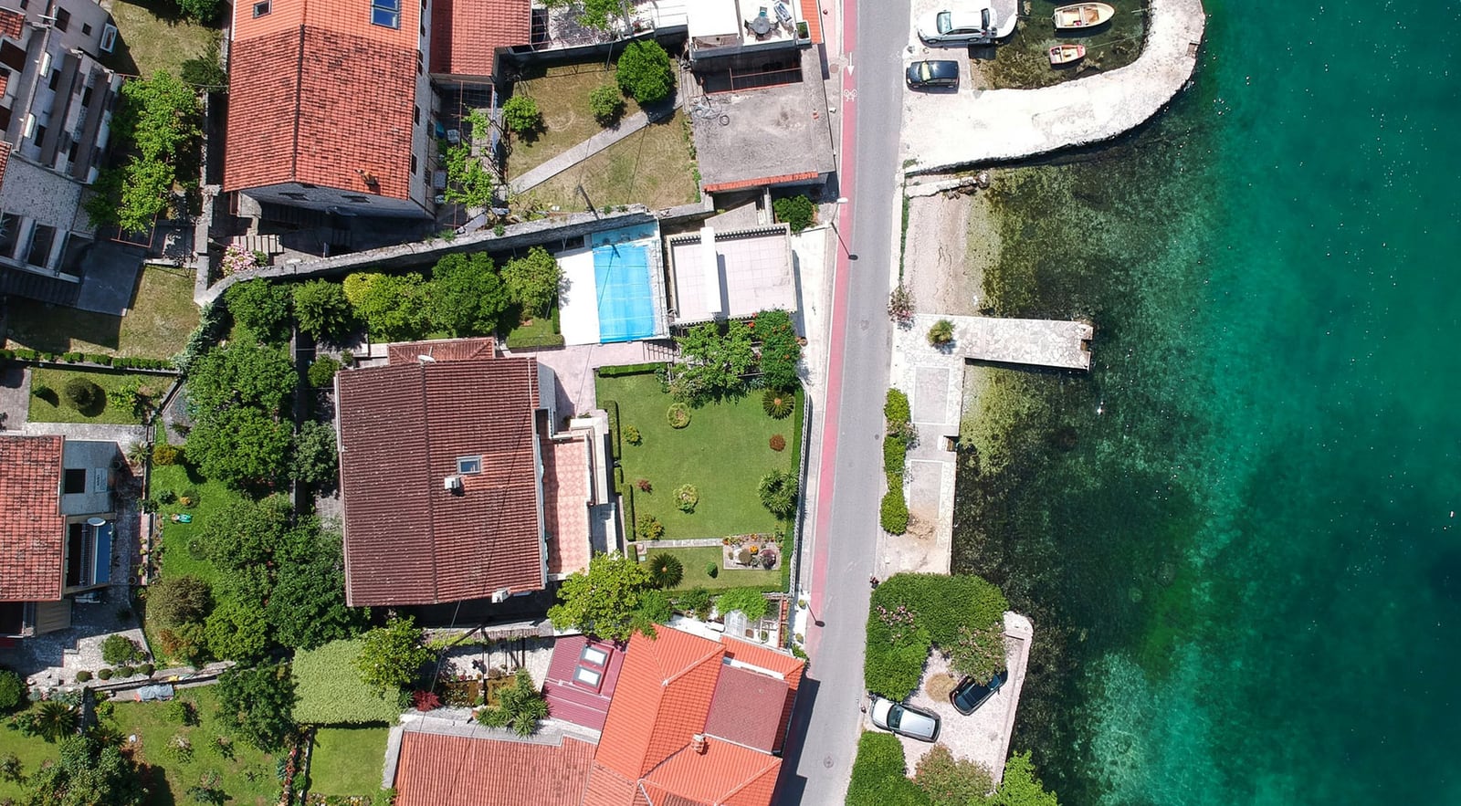 Luftaufnahme einer Villa in Dobrota, Montenegro: Haus mit Ziegeldach, grünem Garten und eigenem Zugang zum Meer.