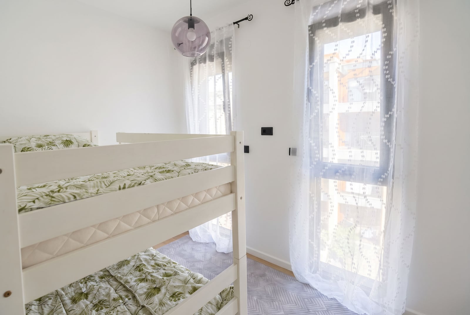 Beli spratni krevet sa posteljinom u svetloj dečijoj spavaćoj sobi u Tivtu, Crna Gora