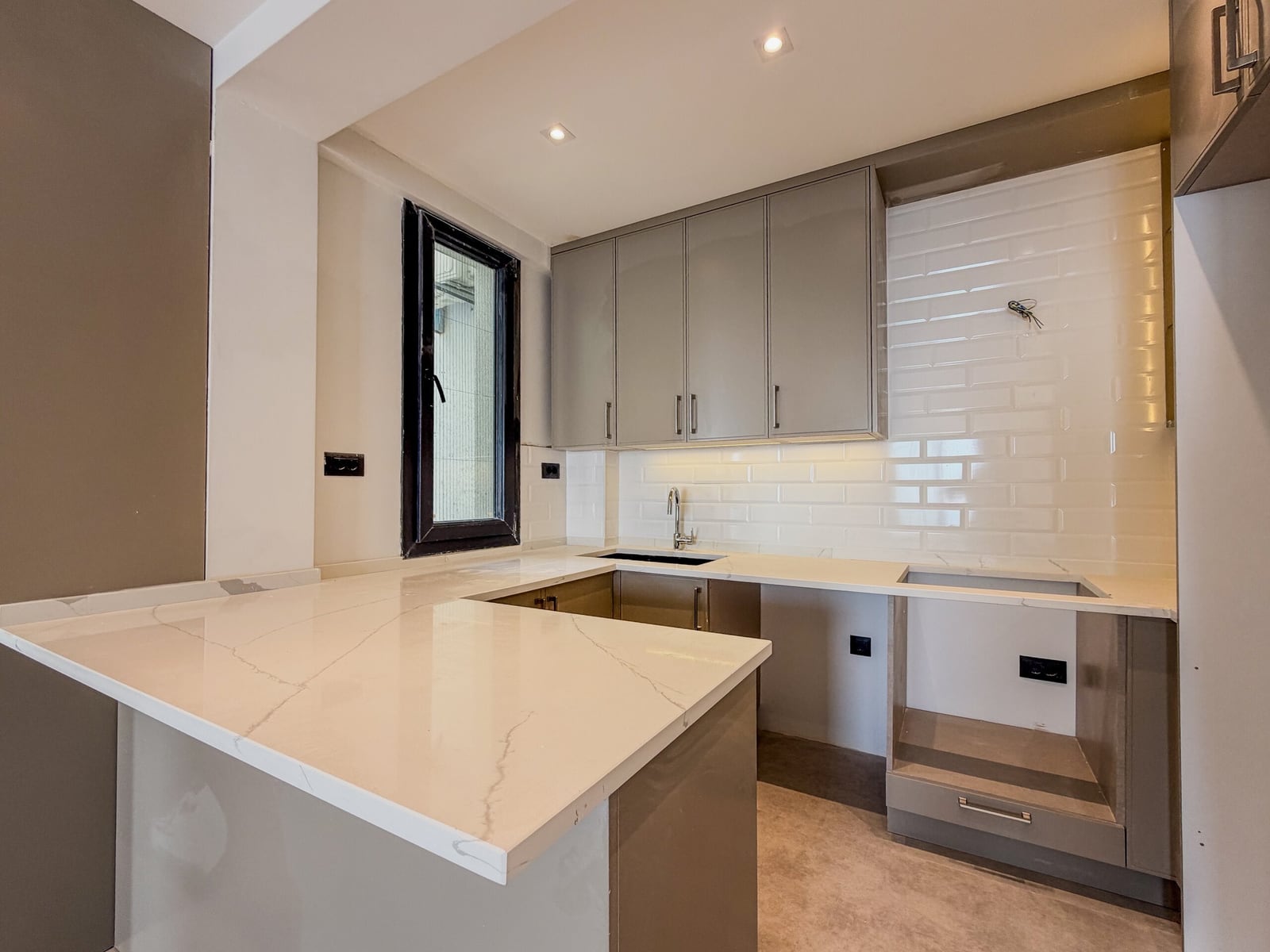 Modern kitchen in an apartment in Budva, Montenegro: gray cabinetry, white marble-look countertop, and subway tile backsplash