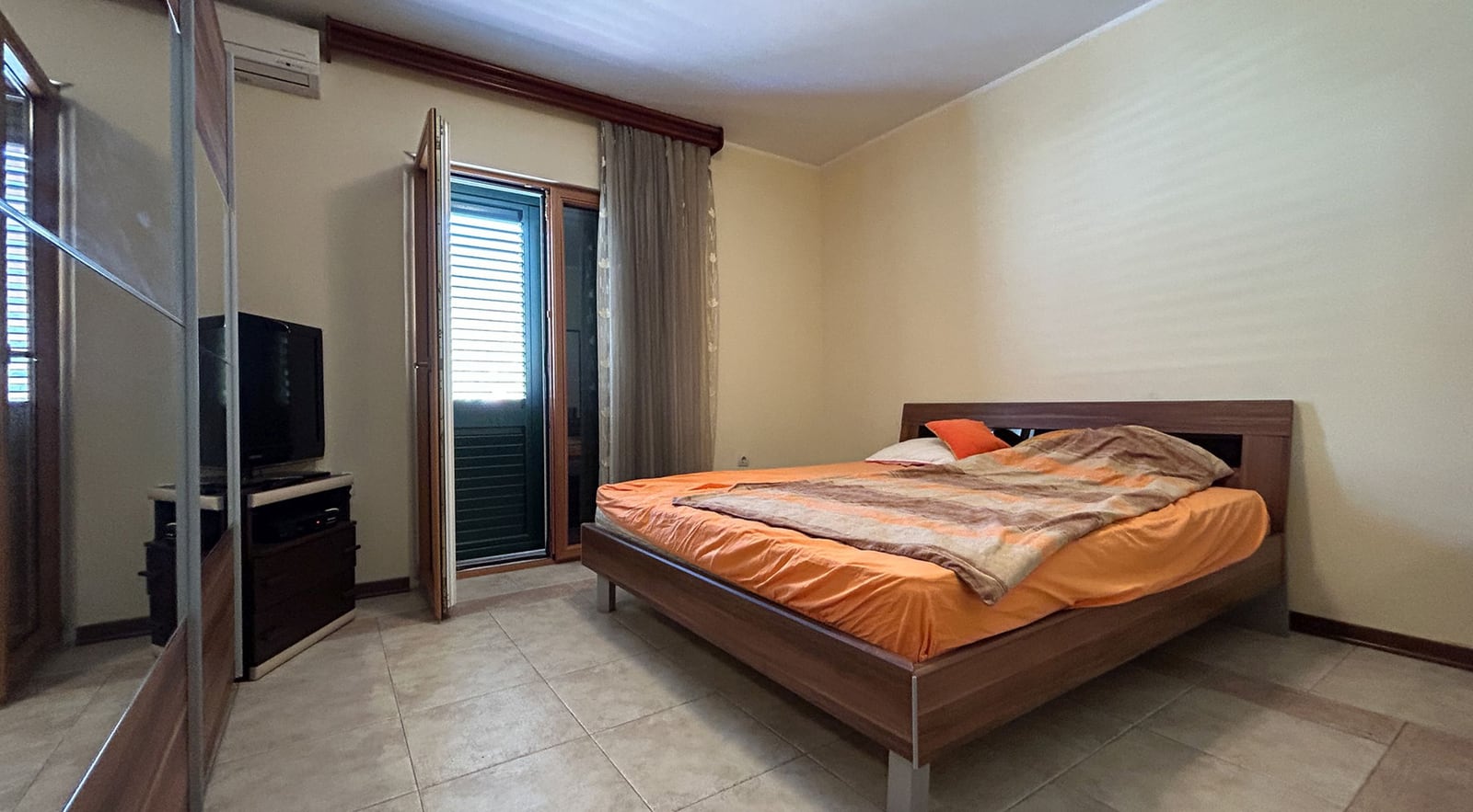 Schlafzimmer mit Doppelbett, Kleiderschrank und Zugang zum Balkon in einer Villa, Stadt Dobrota, Montenegro.